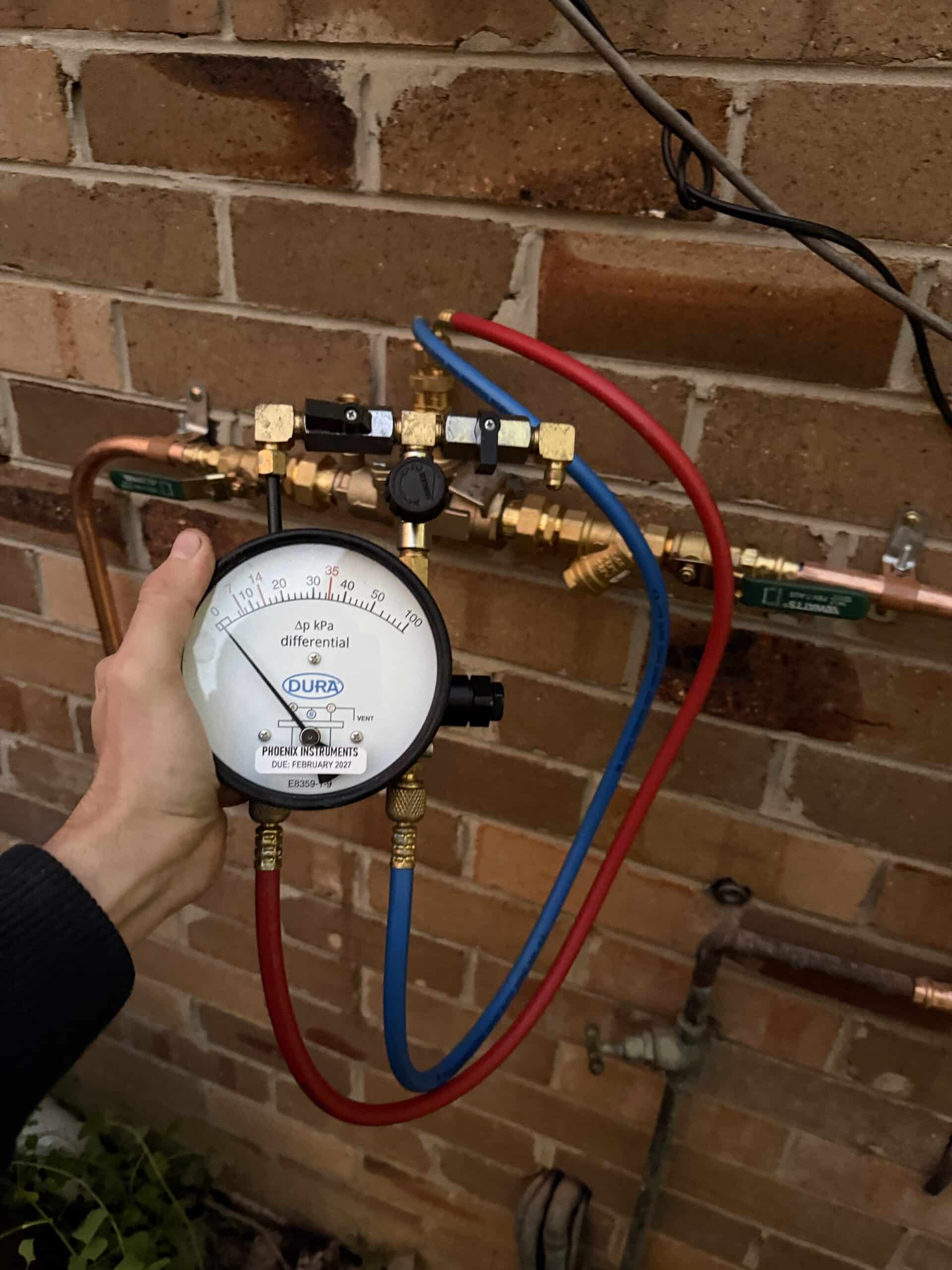 JNG Plumbing Group carrying out annual RPZ backflow testing with a professional test gauge